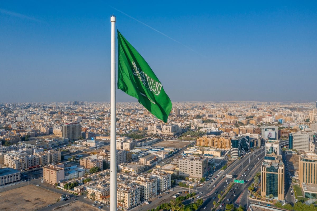 Saudi Arabian flag above Riyadh city, symbolizing national pride and modern growth by Passion Group